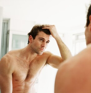 Man checking hair in bathroom mirror