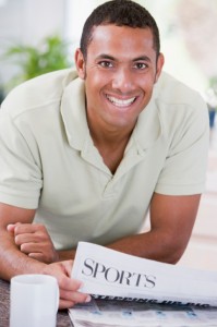 Man reading newspaper in kitchen, smiling