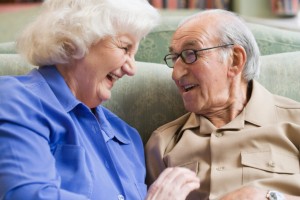elderly couple sitting on sofa, smiling