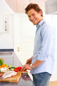 man in kitchen chopping fresh vegetables