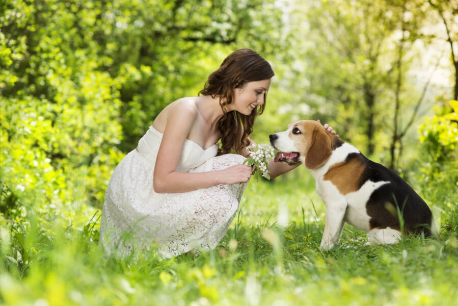 young woman outdoors petting a beagle