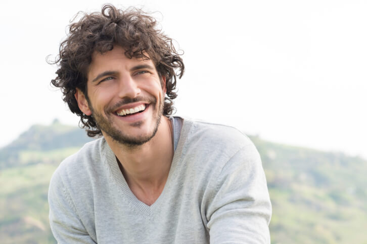 young man sitting outdoors, smiling