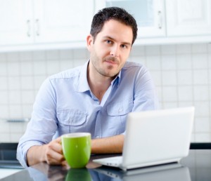 young man sitting at a computer with coffee