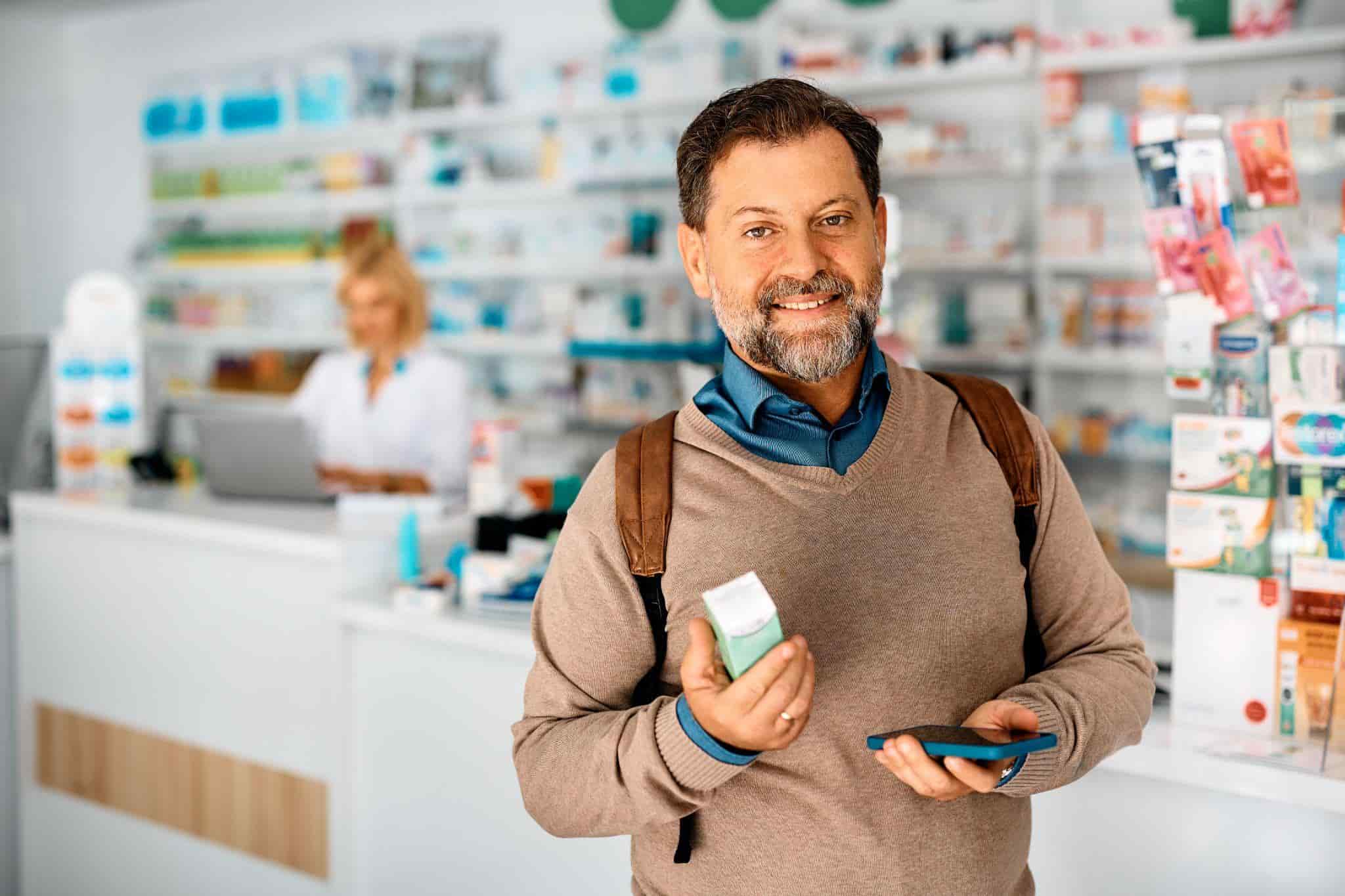 smiling man holding medicine and cellphone