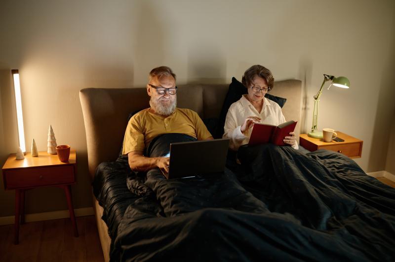 middle-aged couple reading separately in bed
