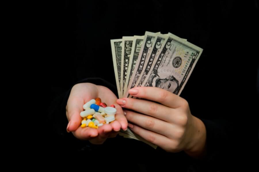 Person holding a fan of money and pills.