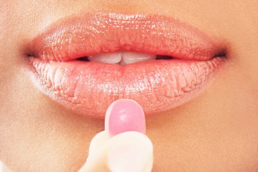 Woman taking a pink pill.