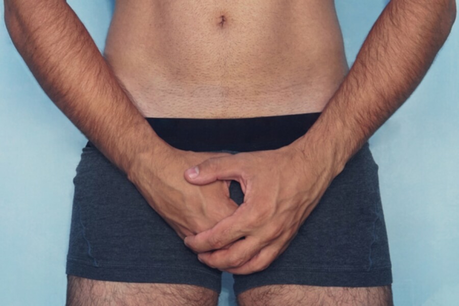 Man holding his hands over his groin.