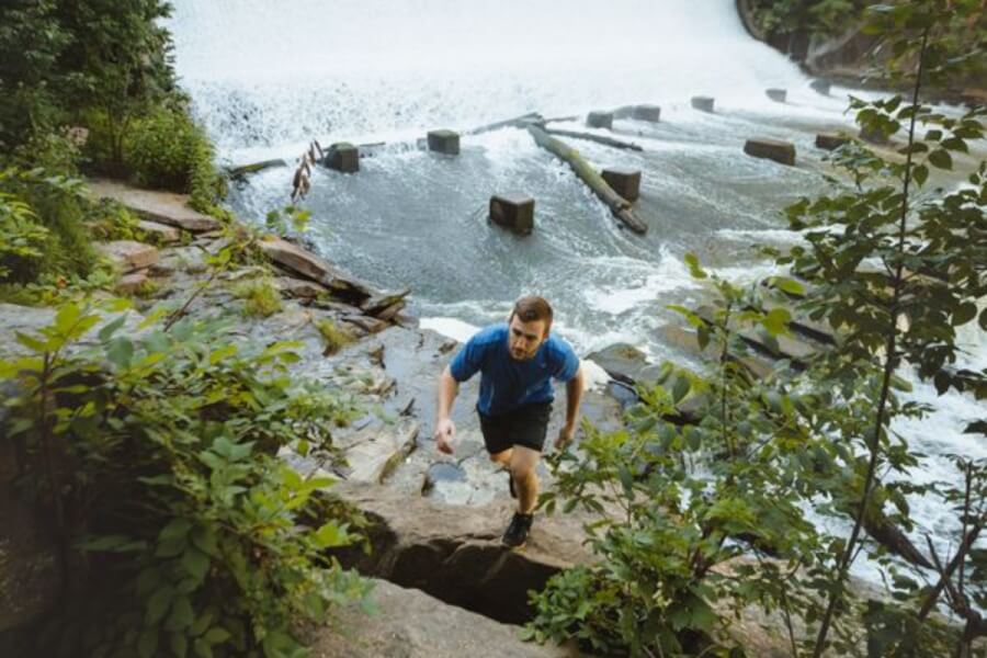 Man hiking with a waterfall in the background.