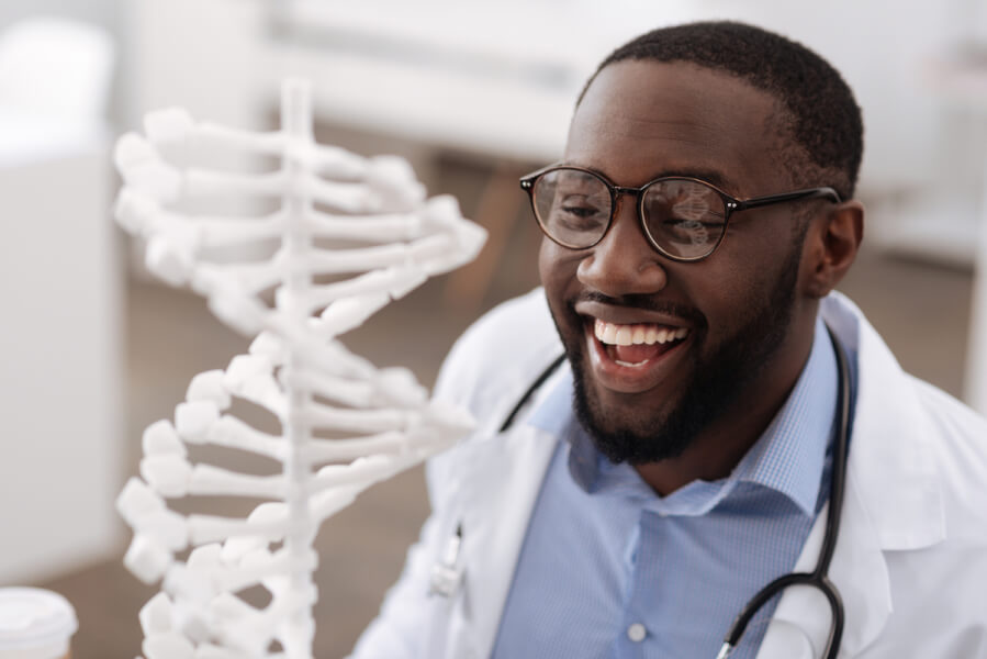Medical doctor smiling next to a DNA model.