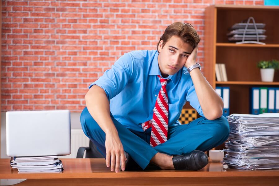 Businessman sitting onto of a desk.