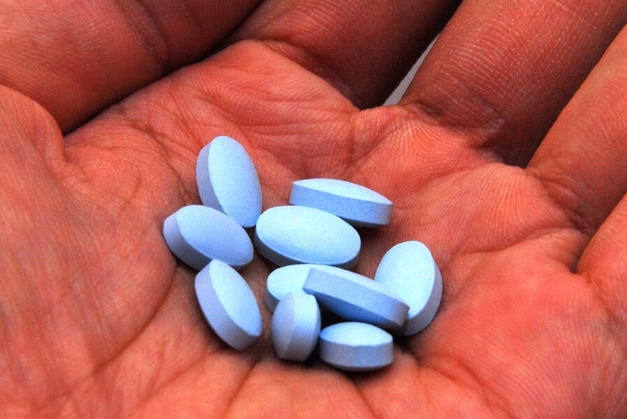 Blue pills in the palm of a hand.