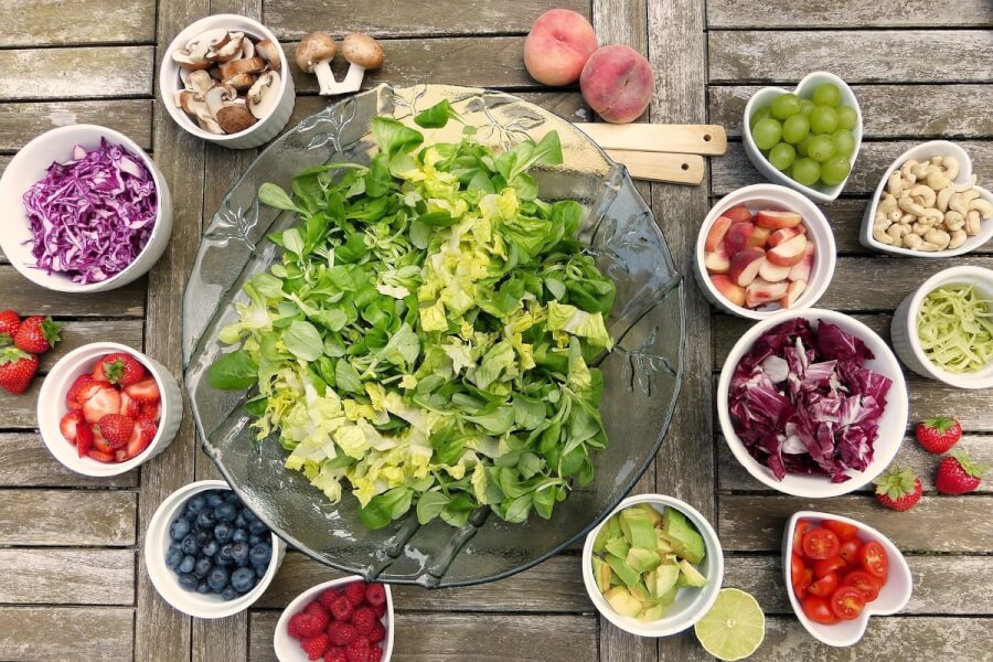 Table top with fresh salad, fruits and nuts.