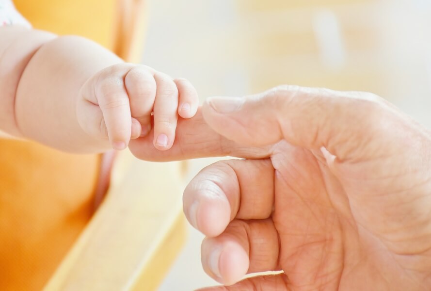 Person holding a babies hand.
