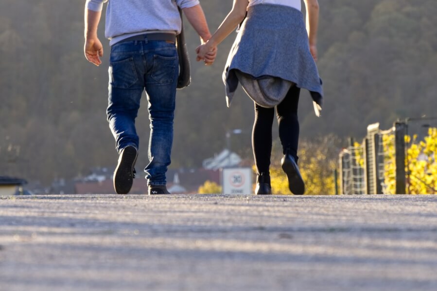 Two people walking holding hands.