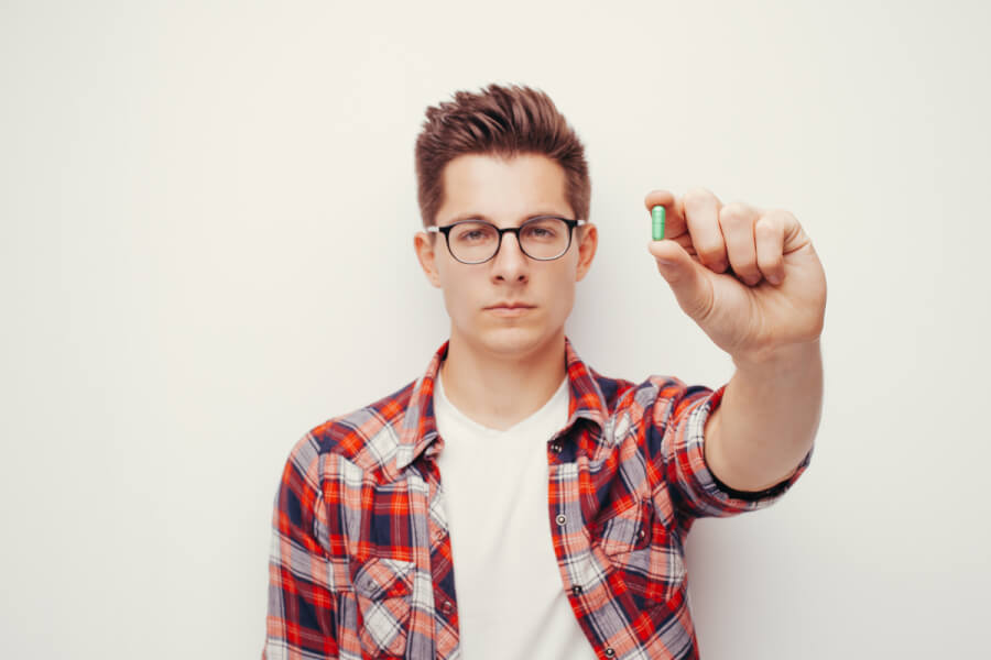 Man holding a pill in one hand.