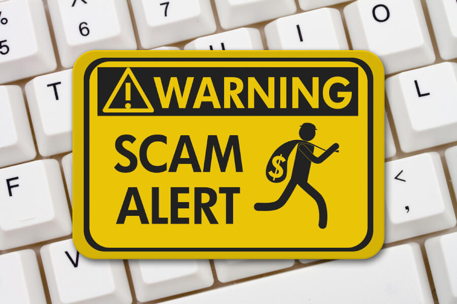Yellow warning sign labeled Scam alert.