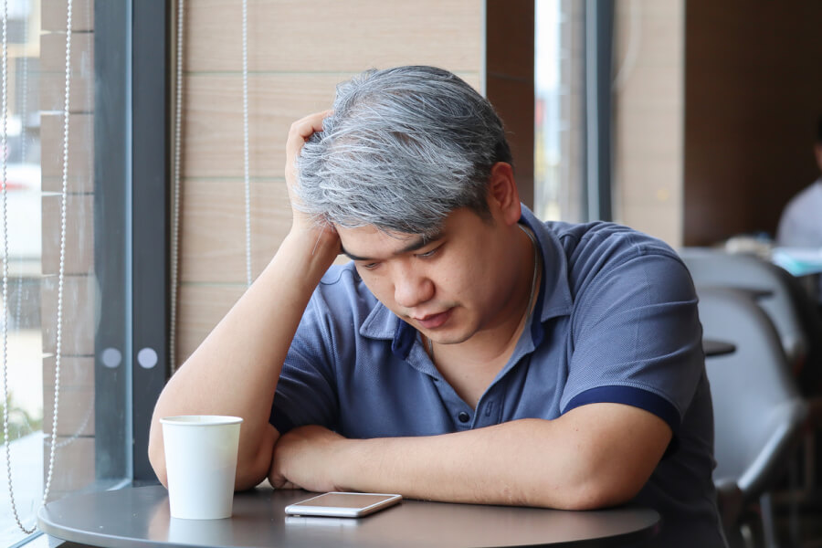 Older man sitting at a table with a coffee.