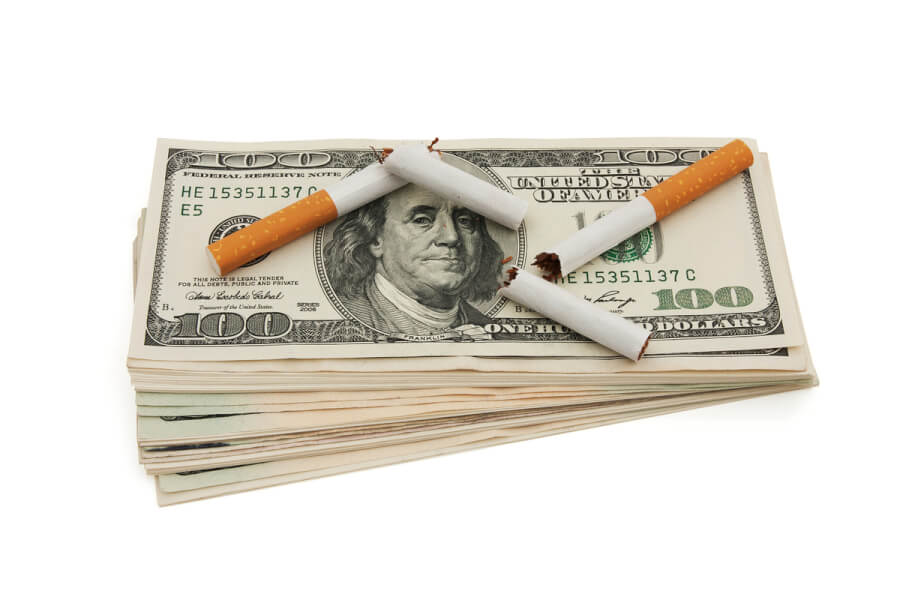 Stack of U.S. 100 dollar bills with cigarettes on top.