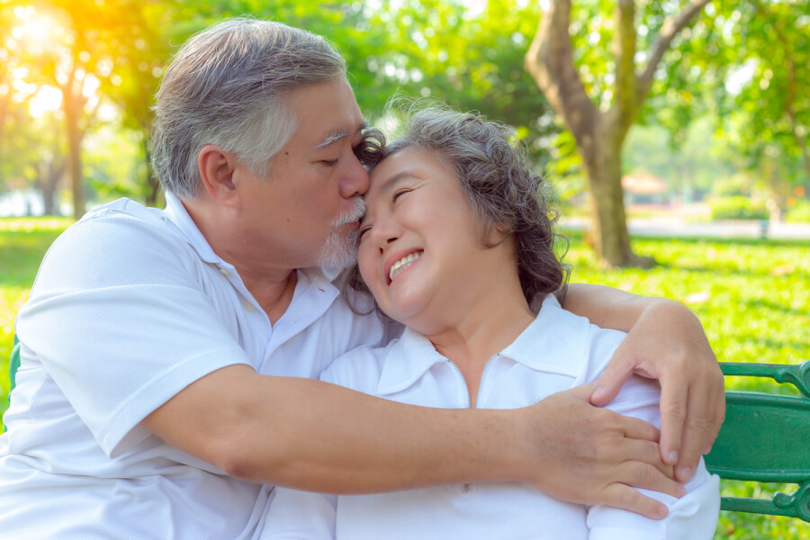 Happy couple sitting outside hugging.