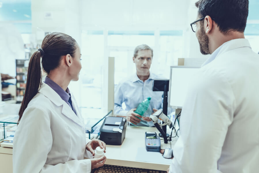 Man discussing medications with two pharmacists.