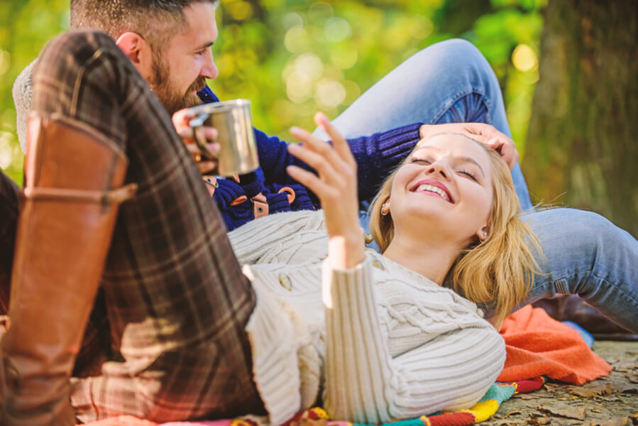 Woman laying down outside with a man talking and laughing.