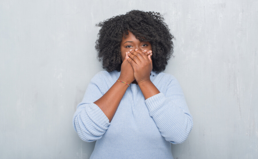 Woman holding her hands over her mouth appearing surprised.