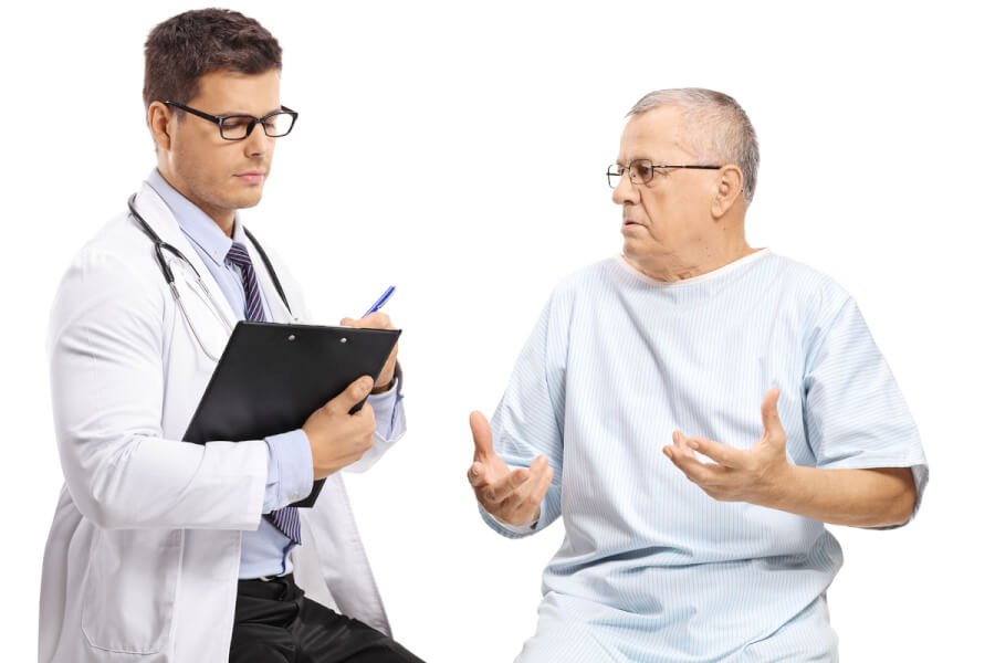 Medical doctor speaking with a patient in a hospital gown.