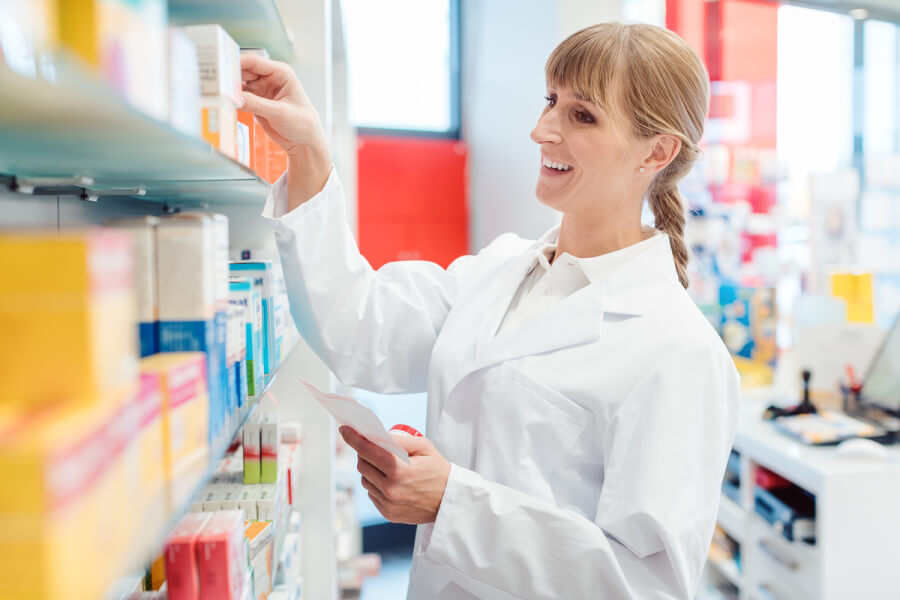 Medical pharmacist looking for medication on a shelf.