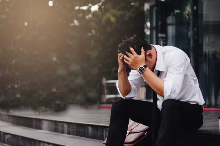 Man sitting on steps with his hands on his head.
