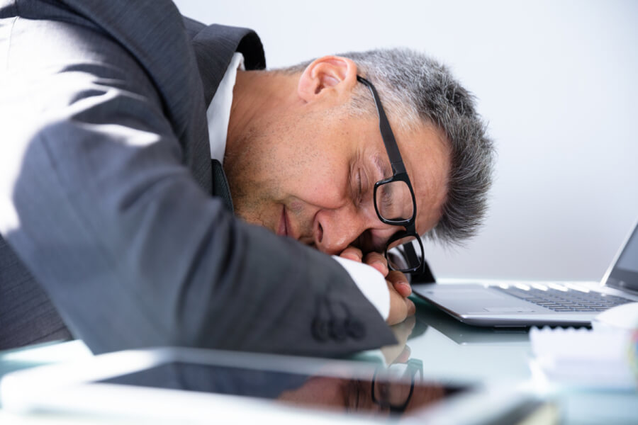 Man lying on his desk asleep.