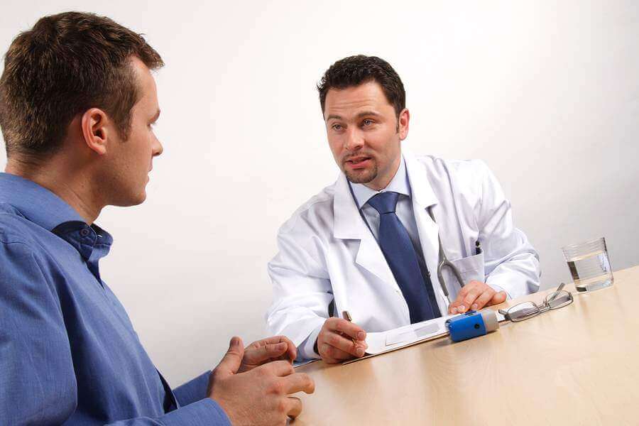 Medical doctor discussing care with a male patient at a table.