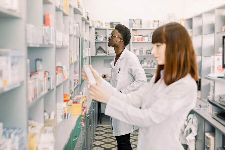 Two pharmacists stocking shelves.