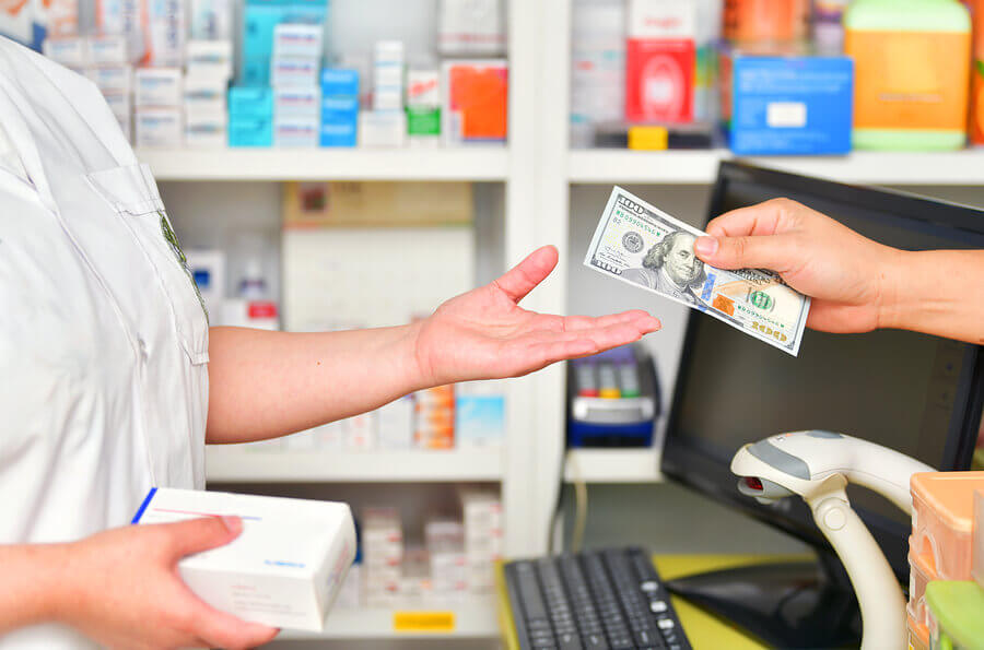 Person handing paper money to a pharmacist for a purchase.