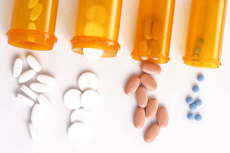 Plastic pill bottles lying on their side with pills pouring out.