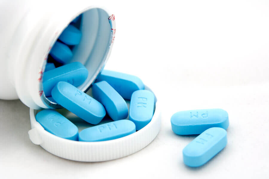Blue pills spilling out of a bottle.