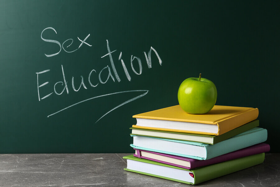 Sex education written on a blackboard with a stack of books.