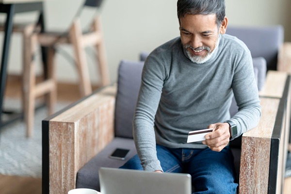 Man on a laptop holding a credit card Man on a laptop holding a credit card