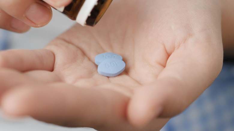 person removing two viagra pills out of a bottle on their hand