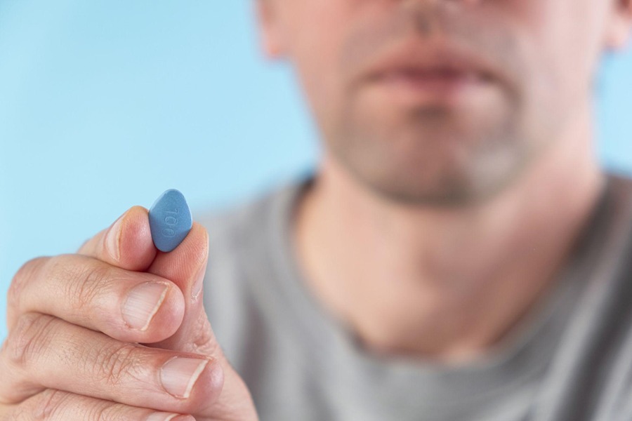 Man holding up a Viagra pill