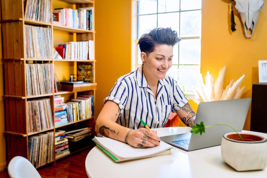 trans man smiling and working on a laptop
