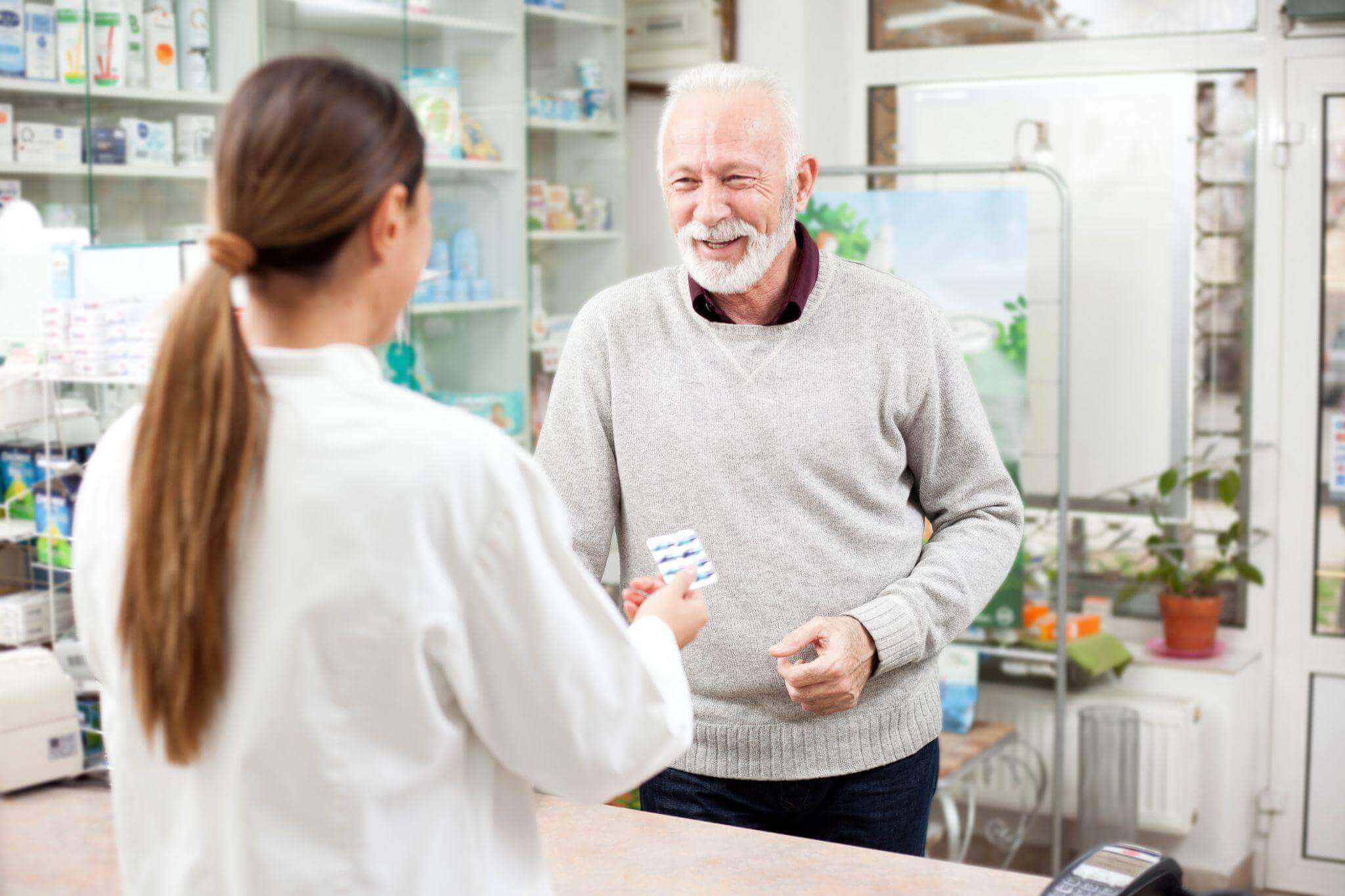 pharmacist handing medicine to elderly client
