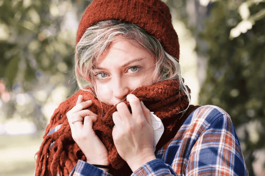 women wearing warm clothes and using her scarf to cover her mouth