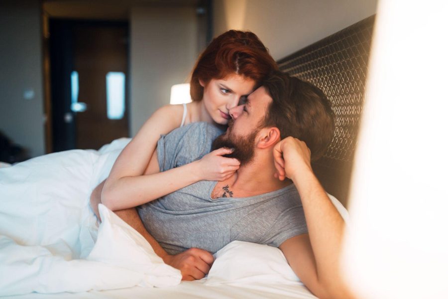 young playfully couple facing each other in bed
