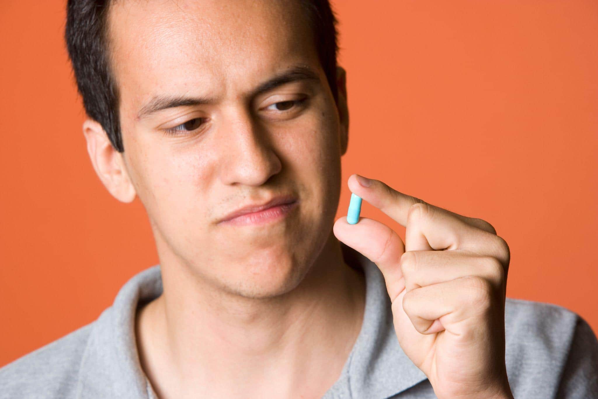 man staring at a sex-enhancer pill