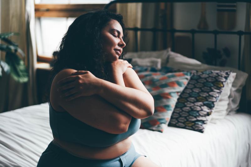 Plus size woman comforting herself when getting out of bed