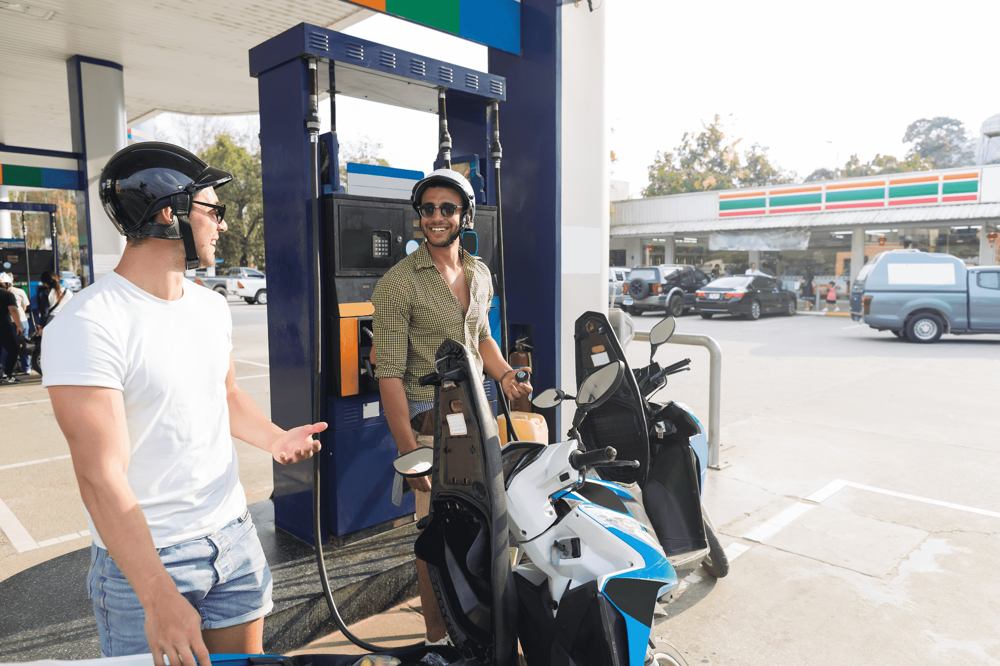 two smiling motorcyclists at a gas station