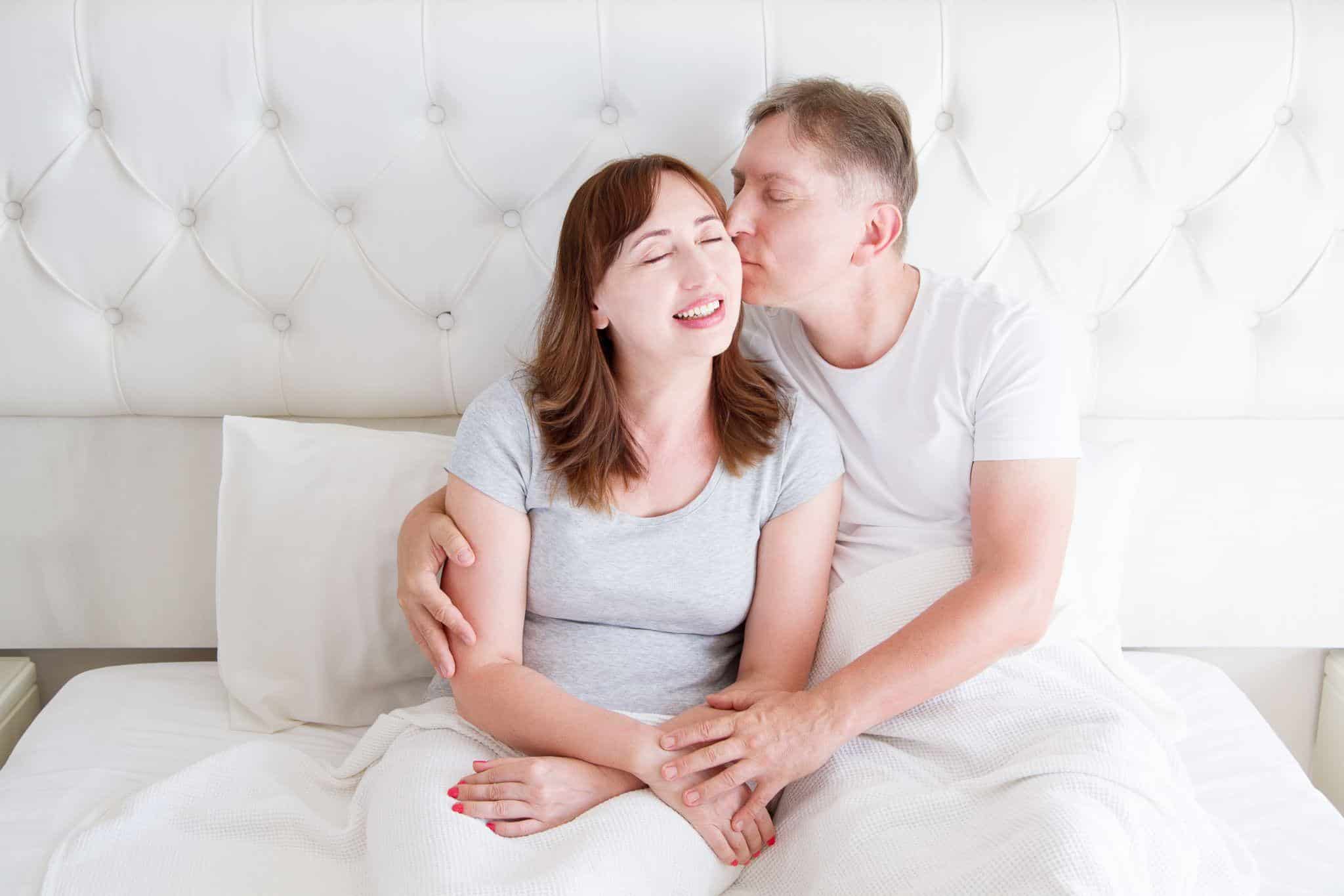 middle aged couple kissing in bed