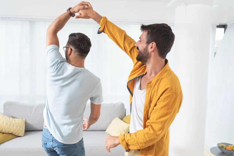 young gay couple dancing in their living room