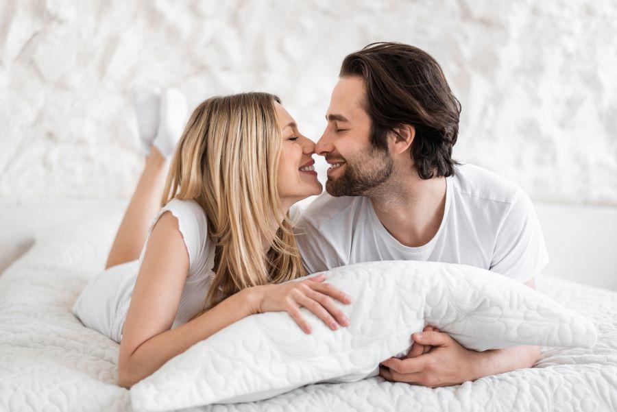 happy young couple kissing in bed